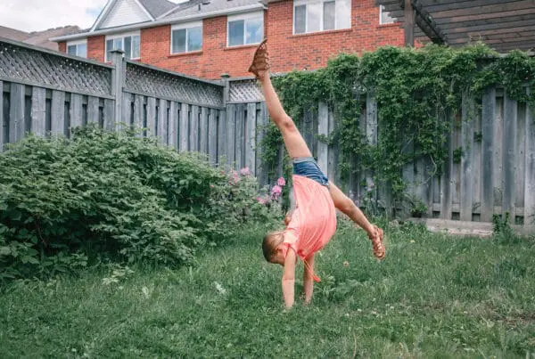 Teenage girl preparing for first gymnastics class by doing cartwheels in the backyard