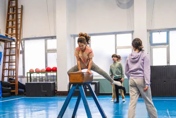 Young girl practicing gymnastics, jumping over a pommel horse