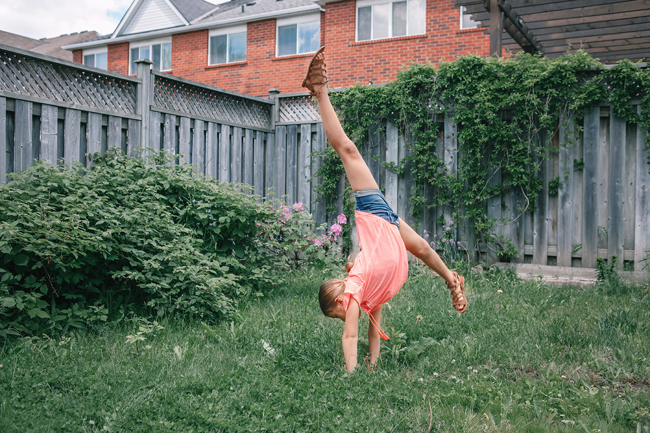 Teenage girl preparing for first gymnastics class by doing cartwheels in the backyard