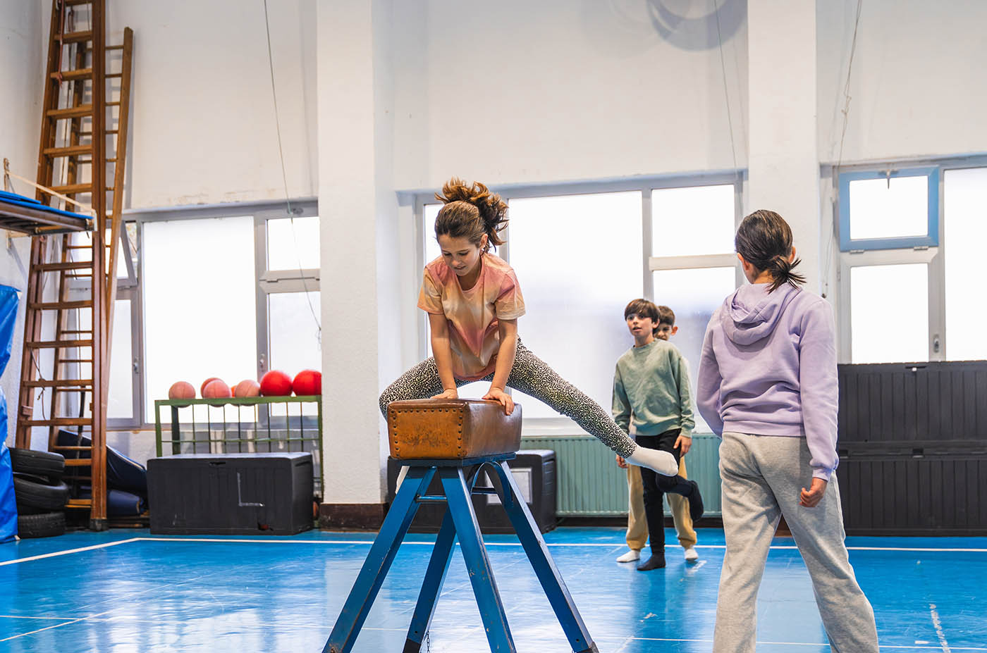 Young girl practicing gymnastics, jumping over a pommel horse